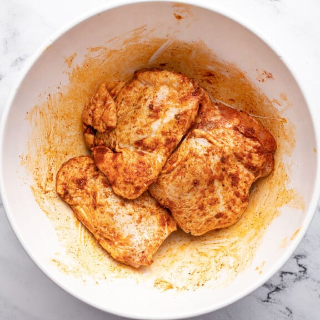 hauts de cuisse de poulet enrobés de mélange d'épices et de fécule de maïs avant cuisson air fryer