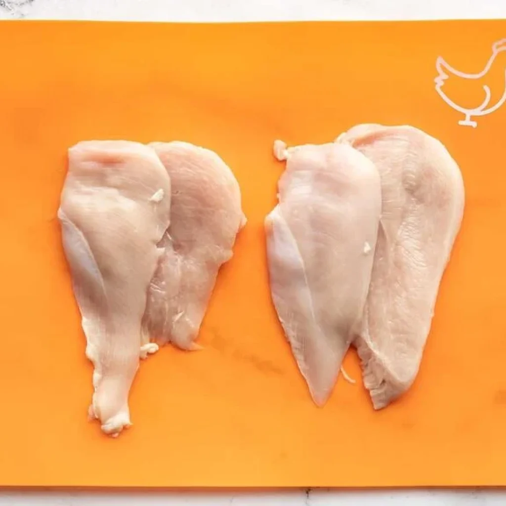 Poitrines de poulet crues sur une planche à découper, prêtes à être marinées ou cuisinées