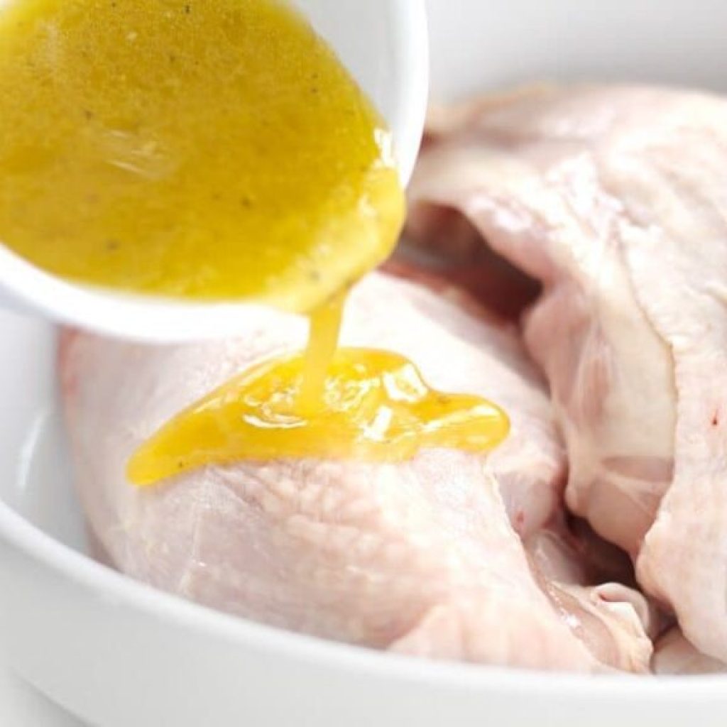 marinade citron versée sur blanc de poulet fendu avec os dans un plat en verre pour cuisson basse température