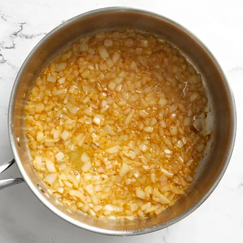 oignons émincés dorés dans une poêle pour la sauce crémeuse spaghetti au poulet