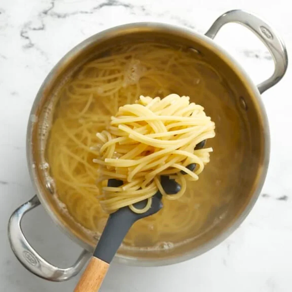 spaghetti cuits al dente dans une casserole, prêts à être égouttés pour la recette de spaghetti au poulet