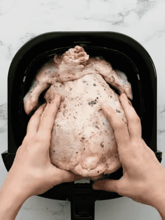 poulet entier placé côté poitrine vers le bas dans le panier d'un air fryer Ninja pour cuisson croustillante
