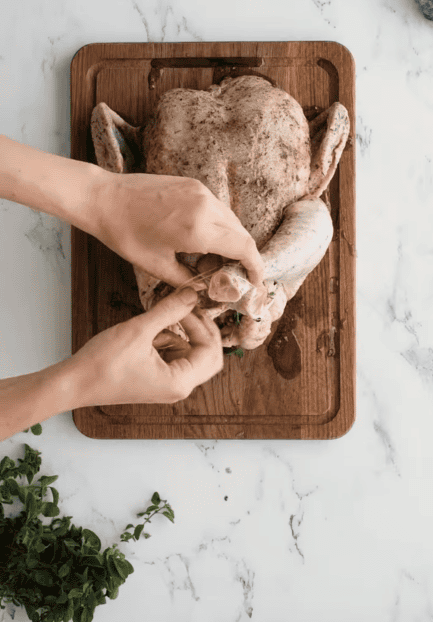 poulet entier farci de thym et d'origan frais, cuisses ficelées avant cuisson air fryer