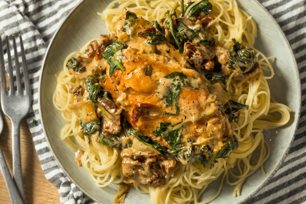 poulet à la toscane crémeux avec tomates séchées et épinards servi sur pâtes sauce Alfredo
