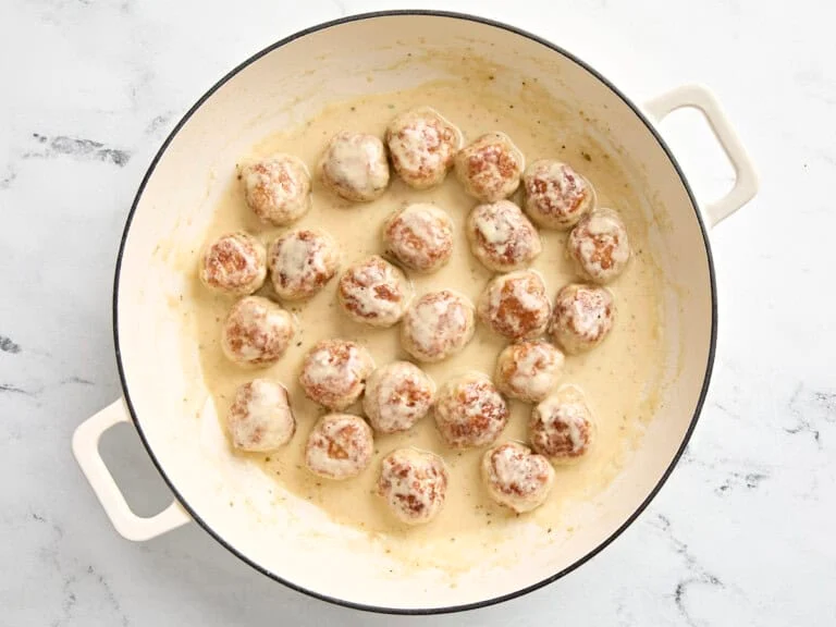 boulettes de poulet haché mijotant dans la sauce crémeuse au bouillon, crème et parmesan