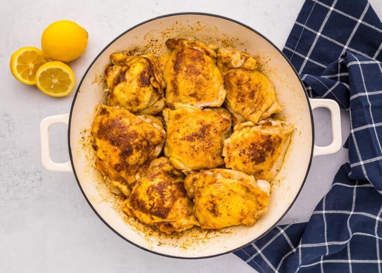 cuisses de poulet marocaines dorées dans une poêle avec olives, citron tranché et pois chiches avant cuisson au four