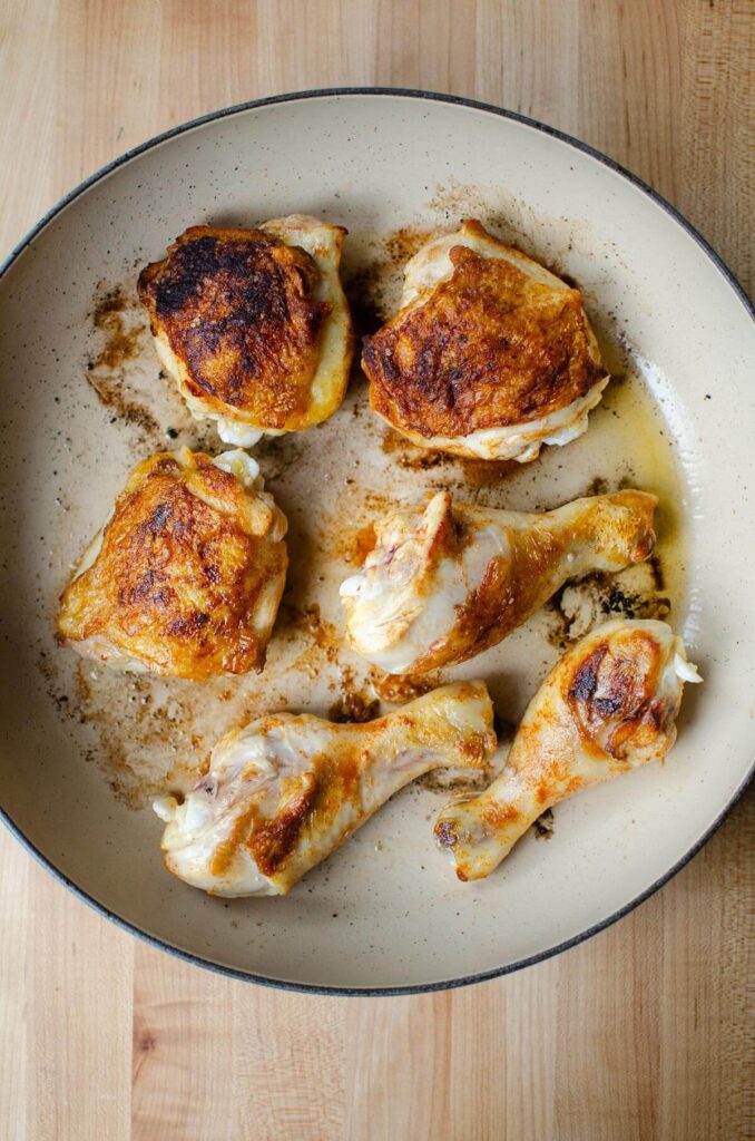 "Morceaux de poulet, cuisses et pilons, dorés dans une poêle. Étape de la préparation du poulet basquaise à l'ancienne."