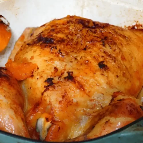 Poulet rôti dans une cocotte en fonte, avec une peau dorée et croustillante.